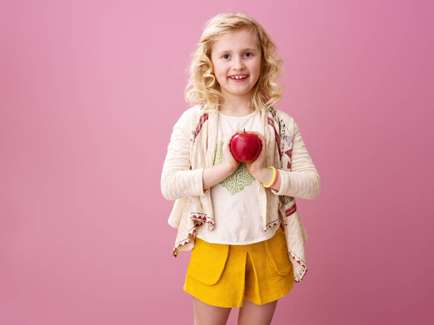 Pink mood. smiling stylish girl with wavy blonde hair on pink background holding an apple - Фото, изображение