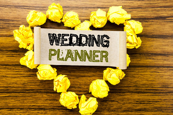 Wort, schreiben Hochzeitsplaner. Geschäftskonzept für die Ehevorbereitung auf klebrigem Zettelpapier auf dunklem Holzgrund. mit gelbem gefaltetem Papierherz, das Liebe oder Anbetung bedeutet. - Foto, Bild