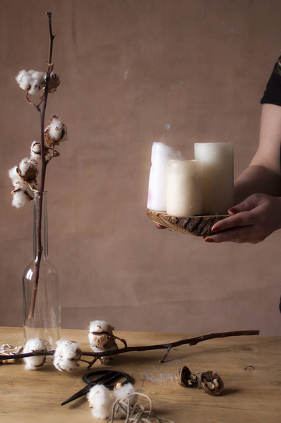 Gros plan de mains féminines mettant des bougies sur la table avec des fleurs de coton
 - Photo, image