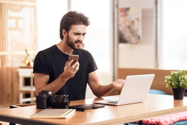 Freelancer bearded man on the phone at laptop sitting at desk. - Foto, imagen