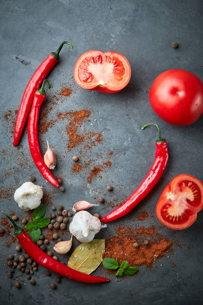 Food cooking background with tomatoes, chili peppers, garlic and spices on dark stone table. - Valokuva, kuva