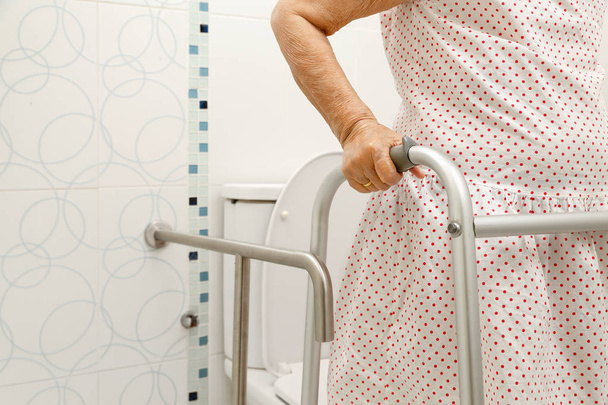 Elderly woman holding on walker in toilet. - Photo, Image