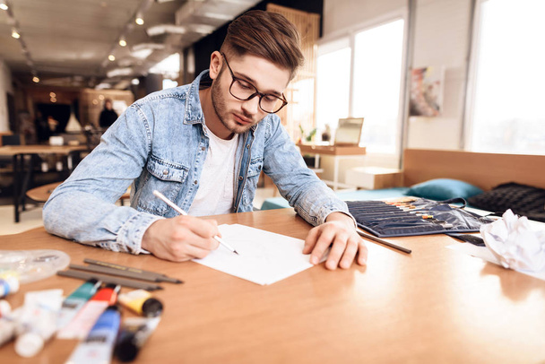 Freelancer man drawing on paper with pencil sitting at desk. - Fotó, kép