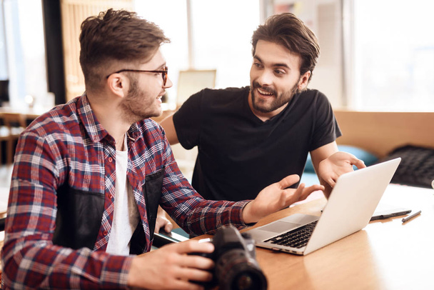 Two freelancer men looking at photos at laptop at desk. - Фото, изображение