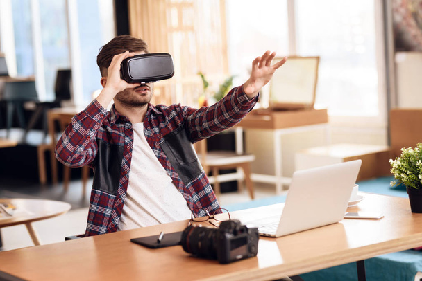 Freelancer man using virtual reality at laptop sitting at desk. - Photo, image