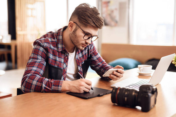 Freelancer man drawing on tablet at laptop sitting at desk. - Zdjęcie, obraz