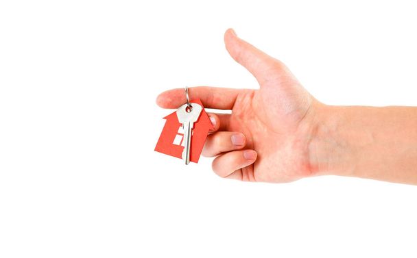 Το χέρι κρατά τα κλειδιά με το μπρελόκ κόκκινο σπίτι. Αγορά - Φωτογραφία, εικόνα