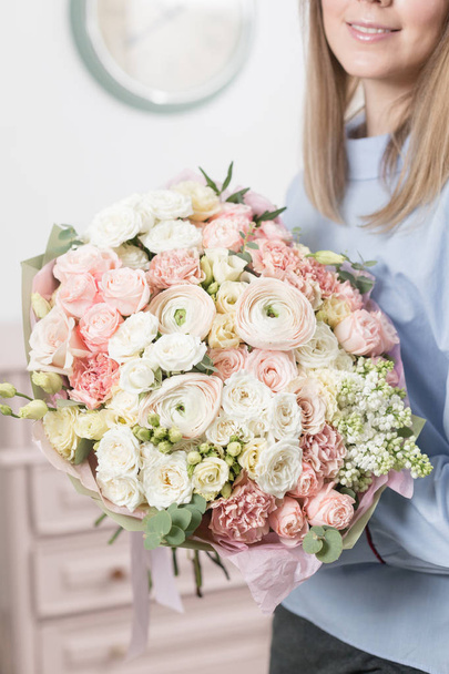 Sunny spring morning. Young happy woman holding a beautiful luxury bouquet of mixed flowers. the work of the florist at a flower shop. vertical photo - Fotoğraf, Görsel