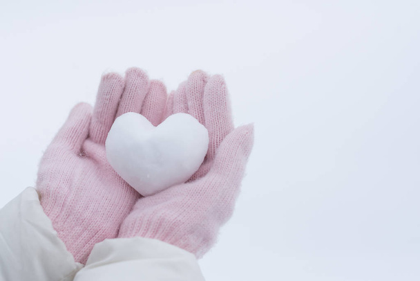 Handen in roze handschoenen houden sneeuw hart - Foto, afbeelding