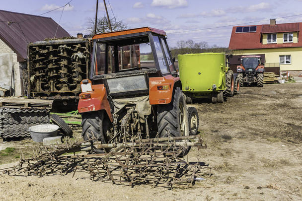 Mezőgazdasági gépek és berendezések a garázs és pajta közelében. Egy tejüzem udvara. Podlasie, Lengyelország. - Fotó, kép