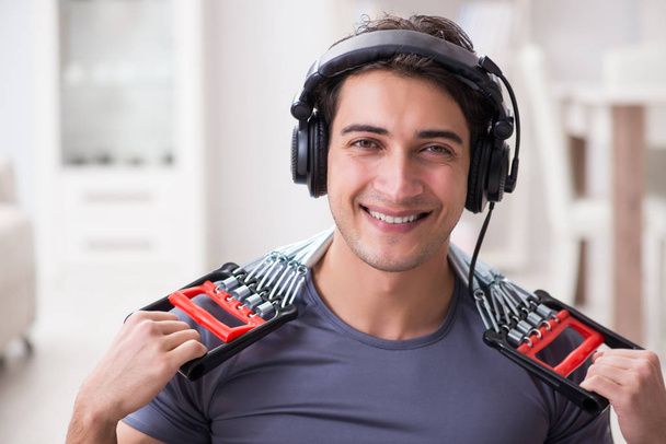Man doing sports with resistance band and listening to music - Photo, Image