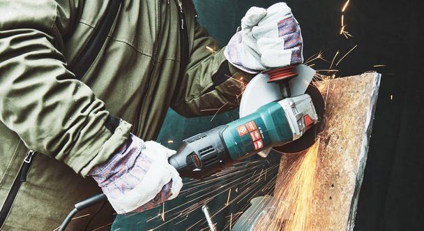 worker grinding cutting metal sheet with grinder machine and sparks - Φωτογραφία, εικόνα