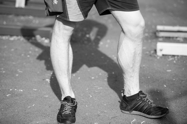 man muscular legs in black sport fashion shoes at stadium - Zdjęcie, obraz