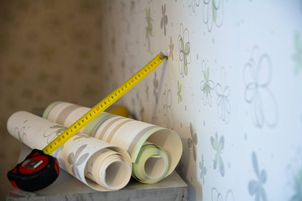 Two rolls of wallpaper and a measuring tape - 写真・画像