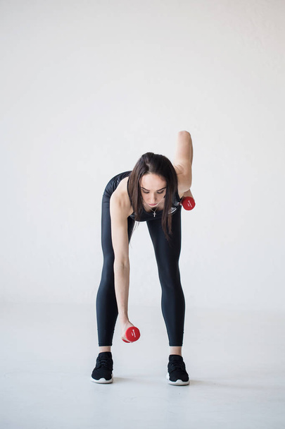 Full-length portrait of the athletic attractive woman doing hand exersices with dumbbells. - Фото, зображення
