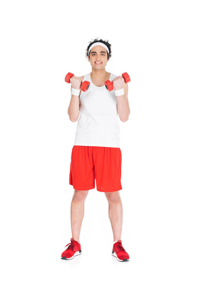 Young thin man in sportswear holding dumbbells isolated on white - Фото, зображення
