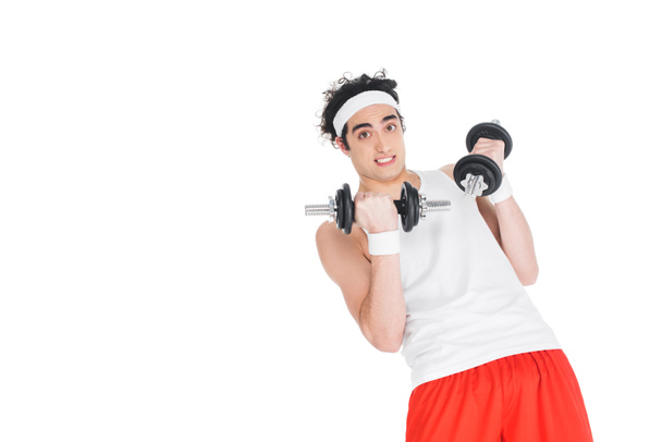 Young skinny man in headband exercising with dumbbells isolated on white - Photo, Image