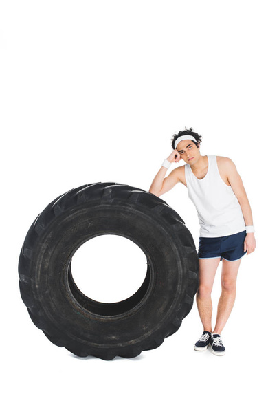 Dünner Sportler steht neben Reifen von Rad isoliert auf weißem Untergrund - Foto, Bild