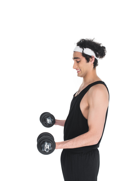 Side view of young skinny sportsman exercising with dumbbells isolated on white - 写真・画像