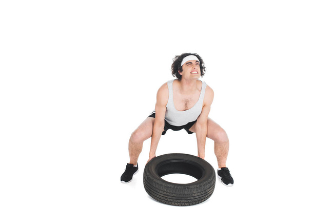 Jonge dunne sportman verhoging tire geïsoleerd op wit - Foto, afbeelding