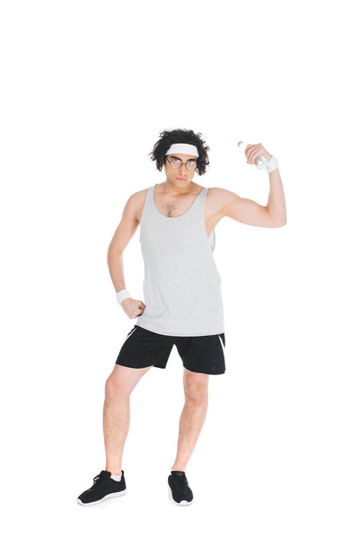 Young thin sportsman in eyeglasses holding bottle of water and showing muscles isolated on white - Foto, Imagem