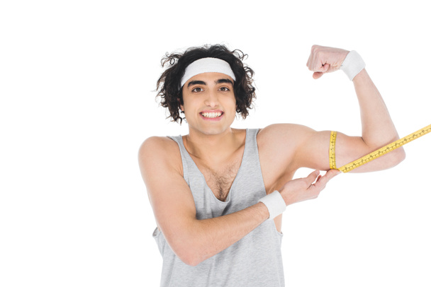 Sorridente sportivo sottile che misura i muscoli a portata di mano isolati su bianco
 - Foto, immagini