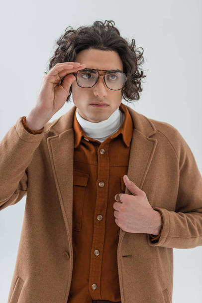 Young stylish man holding eyeglasses isolated on grey - Zdjęcie, obraz