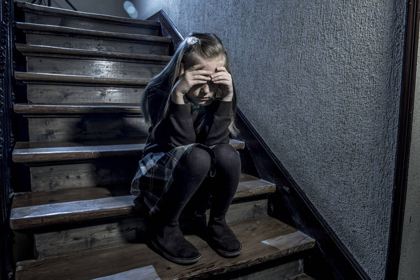 Niña de 7 u 8 años triste deprimida y preocupada sentada en la escalera desesperada y asustada sufriendo acoso escolar
  - Foto, imagen
