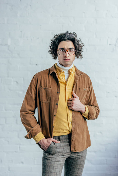 Portrait of young stylish man in eyeglasses in front of brick wall - Фото, зображення