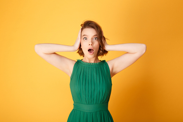 portrait of young shocked woman covering ears with hands isolated on orange - Foto, immagini