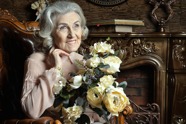 Portrait of senior woman with flowers at home - Fotó, kép