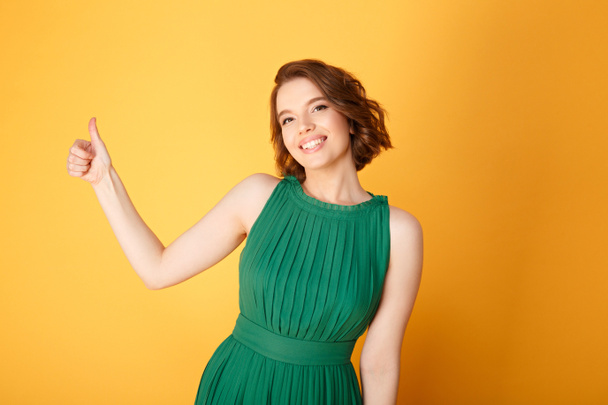 портрет красивой улыбающейся женщины, показывающей большой палец на оранжевом
 - Фото, изображение