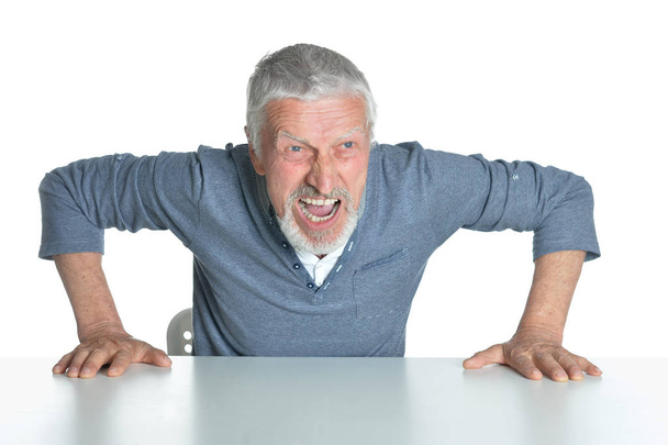 Portrét starší muž, sedící u stolu izolovaných na bílém pozadí - Fotografie, Obrázek