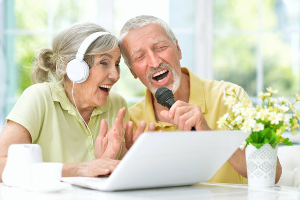 happy senior couple singing karaoke with laptop  at home - Valokuva, kuva