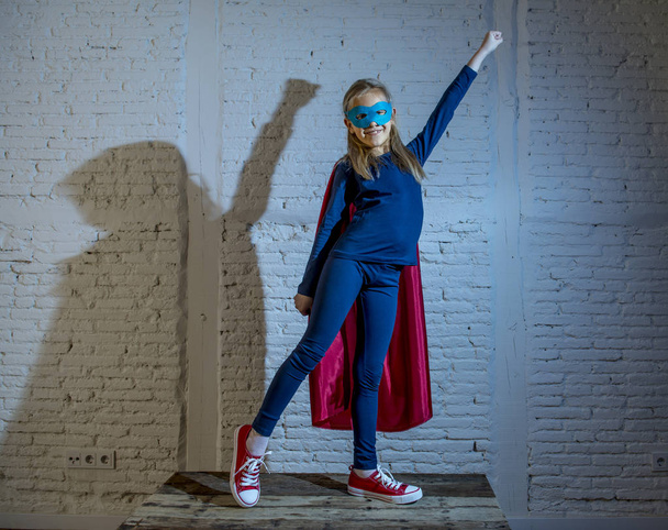 niña de 7 u 8 años de edad, joven que realiza una pose feliz y emocionada con gorra y máscara en disfraz de fantasía de superhéroe luciendo juguetona
  - Foto, Imagen