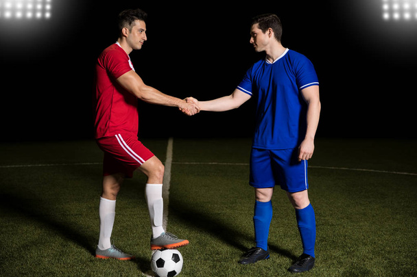 Football team captains standing at center line with ball and handshake before soccer match - Photo, Image