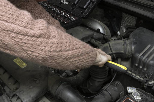自動車整備士は、ツールで車のエンジンを修正します。 - 写真・画像
