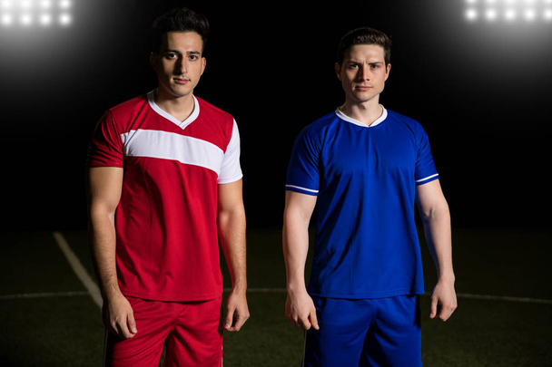 Два соперника футбольной команды стоят вместе на поле
  - Фото, изображение