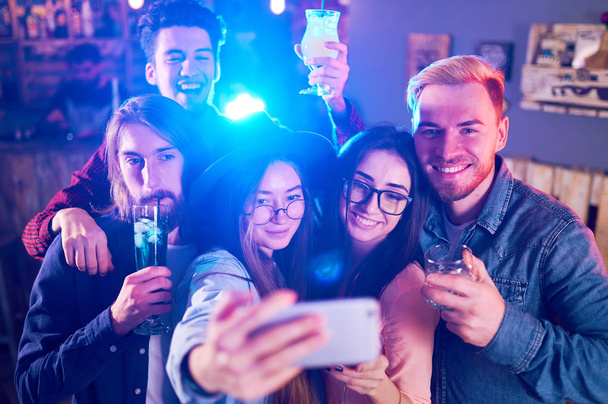 Selfie час. Молодий групою друзів, вечірки в нічному клубі і тостів напої. Щасливі молодих людей з коктейлями в паб. Люди мають відмінний настрій, і вони посмішка багато - Фото, зображення