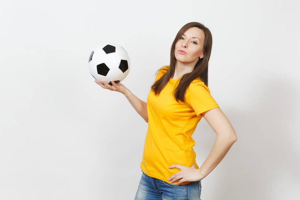 Mooie Europese jonge vrolijke gelukkige vrouw, voetbalfan of speler in geel uniform voetbal houden geïsoleerd op een witte achtergrond. Sport, voetbal, gezondheid, gezonde levensstijl concept spelen. - Foto, afbeelding