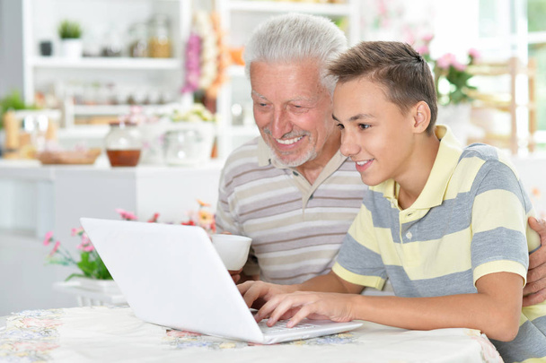 Evde dizüstü bilgisayarı olan bir çocuk ve büyükbabanın portresi. - Fotoğraf, Görsel