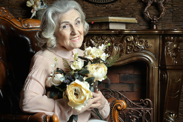 Portrait of senior woman with flowers at home - Fotó, kép