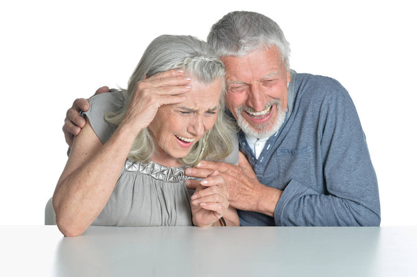 Portrait of hugging senior couple sitting at table isolated on white background - Photo, image
