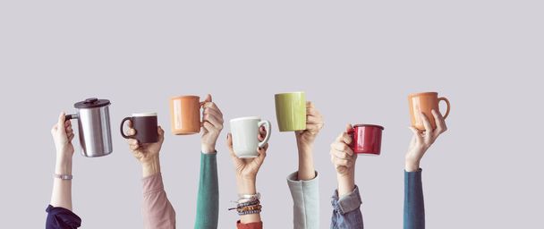 Many different arms raised up holding coffee cup - Fotoğraf, Görsel