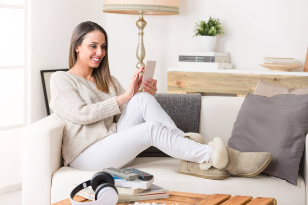 Woman using a smart phone on a couch - Photo, Image