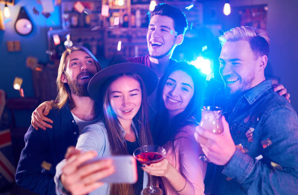 Selfie Time. Young Group of Friends Partying In A Nightclub And Toasting Drinks. Happy Young People With Cocktails At Pub. The People Have A Great Mood And They Smile A Lot - Photo, Image