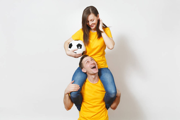 Натхненна молода пара, жінка сидить на людських плечах, фанати з футбольним м'ячем підбадьорюють улюблену футбольну команду, виражаючи жестикулюючі руки ізольовані на білому тлі. Сімейне дозвілля, концепція способу життя
. - Фото, зображення