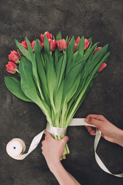 cropped shot of person decorating bouquet of beautiful tulips with ribbon - Photo, image