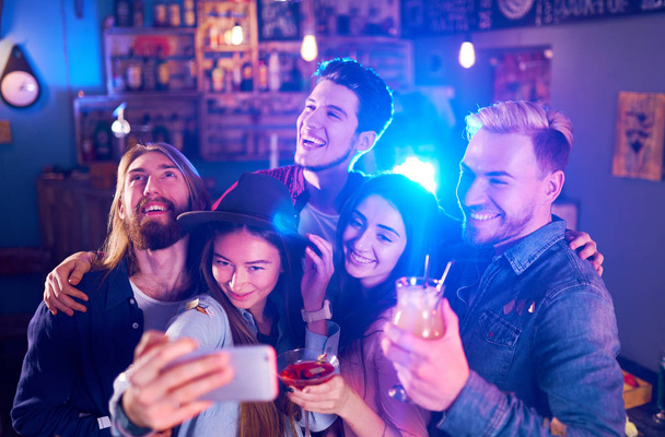 Selfie Time. Young Group of Friends Partying In A Nightclub And Toasting Drinks. Happy Young People With Cocktails At Pub. The People Have A Great Mood And They Smile A Lot - Foto, afbeelding