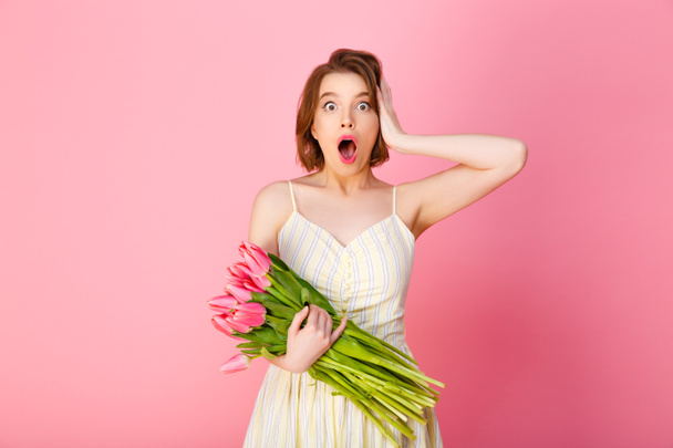 portrait of shocked woman with bouquet of pink tulips isolated on pink - Photo, Image